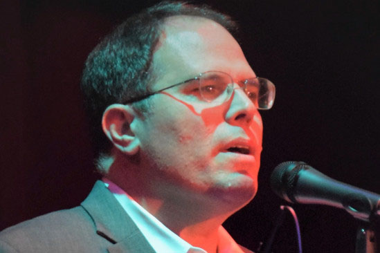 Head shot of singer Jeff Weintraub winging with microphone